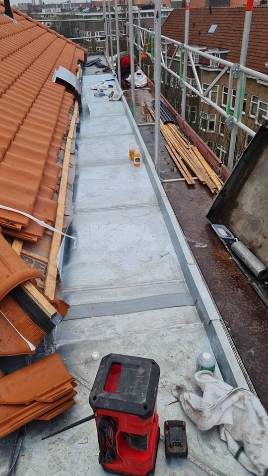 Zinken goot tussen twee pannendaken, met steiger en gereedschap